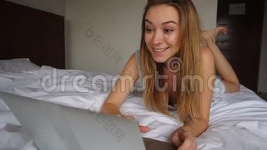 乔昆德女孩在网上通过笔记本电脑赢得赌注，躺在酒店的白色被子里。